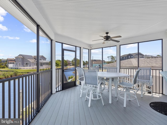 sunroom with ceiling fan, a water view, and a wealth of natural light