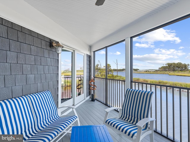 sunroom / solarium featuring ceiling fan and a water view