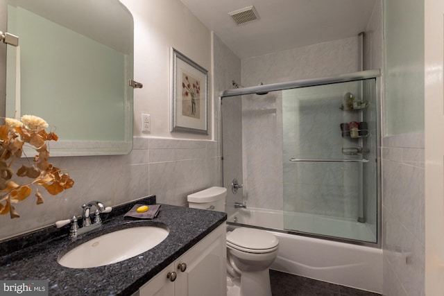 full bathroom with shower / bath combination with glass door, vanity, tile walls, and toilet