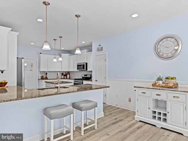 kitchen with white cabinets, appliances with stainless steel finishes, dark stone counters, and sink