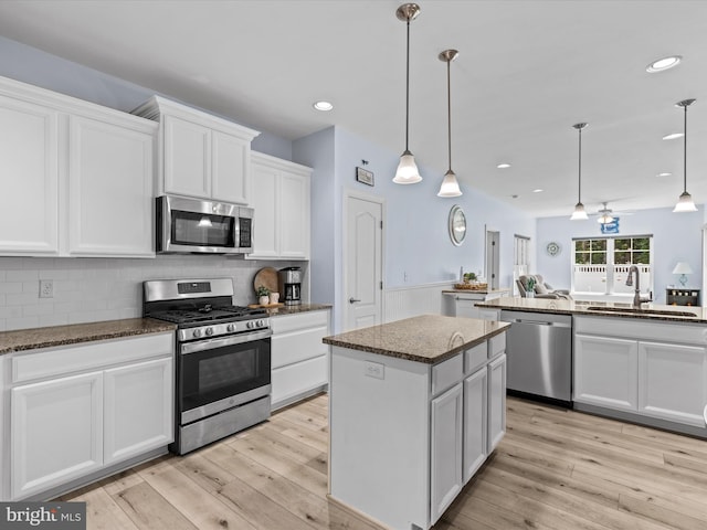 kitchen featuring pendant lighting, white cabinets, sink, a kitchen island, and stainless steel appliances