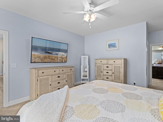 bedroom featuring light carpet, ensuite bathroom, and ceiling fan