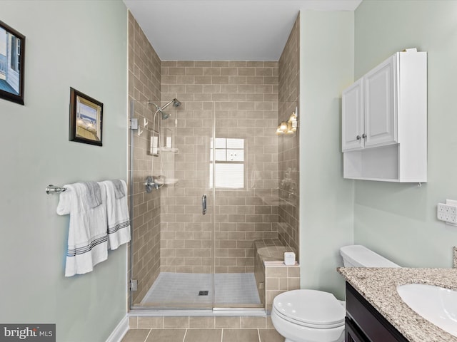 bathroom featuring tile patterned flooring, vanity, toilet, and a shower with door