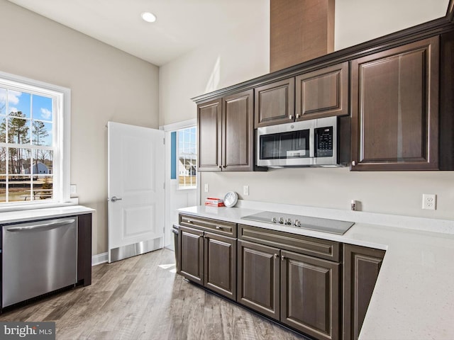 kitchen featuring dark brown cabinets, light hardwood / wood-style flooring, and appliances with stainless steel finishes