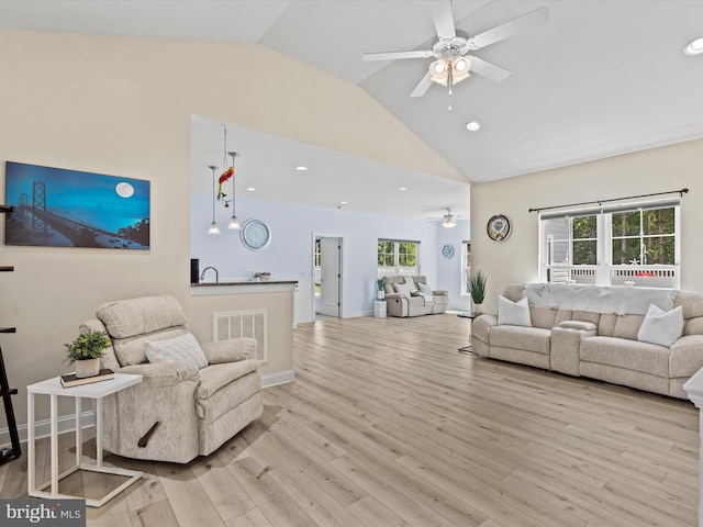 living room featuring light wood-type flooring, ceiling fan, lofted ceiling, and sink