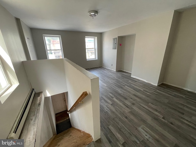 stairway with hardwood / wood-style floors, electric panel, and a baseboard radiator