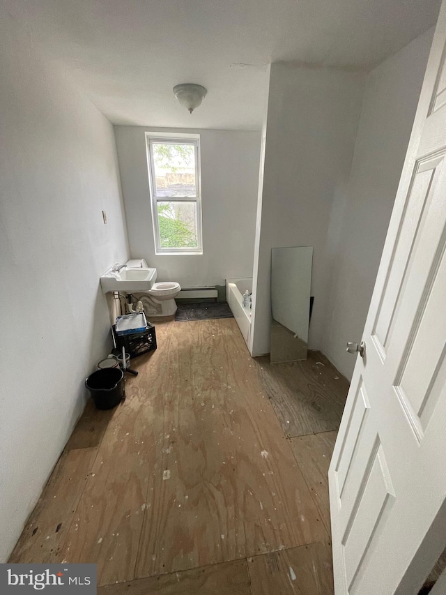 bathroom featuring toilet, a bidet, a baseboard heating unit, and sink