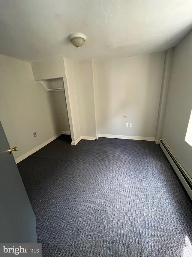 unfurnished bedroom featuring a closet, dark carpet, and a baseboard radiator