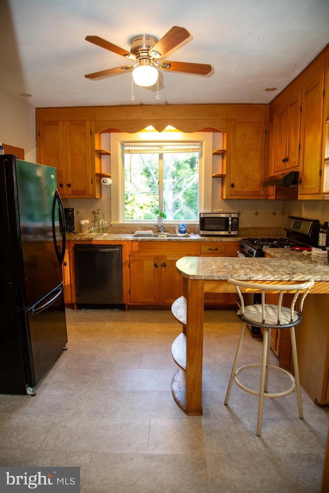 kitchen featuring kitchen peninsula, ceiling fan, sink, black appliances, and a breakfast bar area