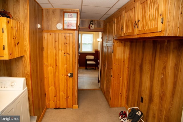 clothes washing area featuring washer / clothes dryer, wood walls, light colored carpet, and cabinets