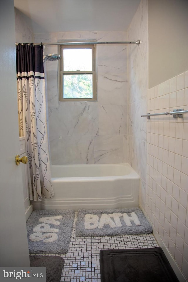 bathroom featuring shower / bathtub combination with curtain and tile walls