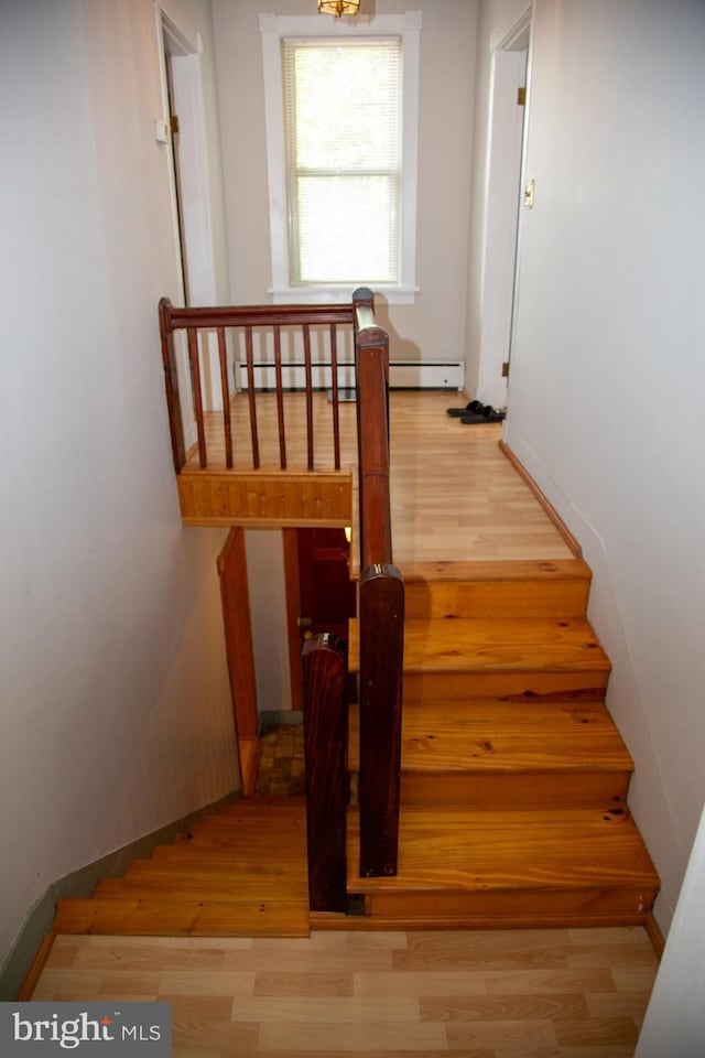 staircase featuring hardwood / wood-style floors and a baseboard heating unit