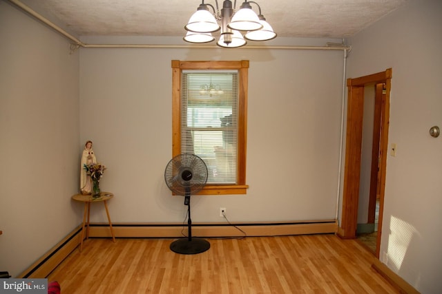 misc room with light wood-type flooring, a textured ceiling, a baseboard radiator, and an inviting chandelier