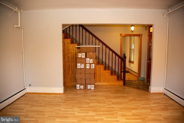 empty room featuring wood walls, light hardwood / wood-style flooring, and a baseboard heating unit