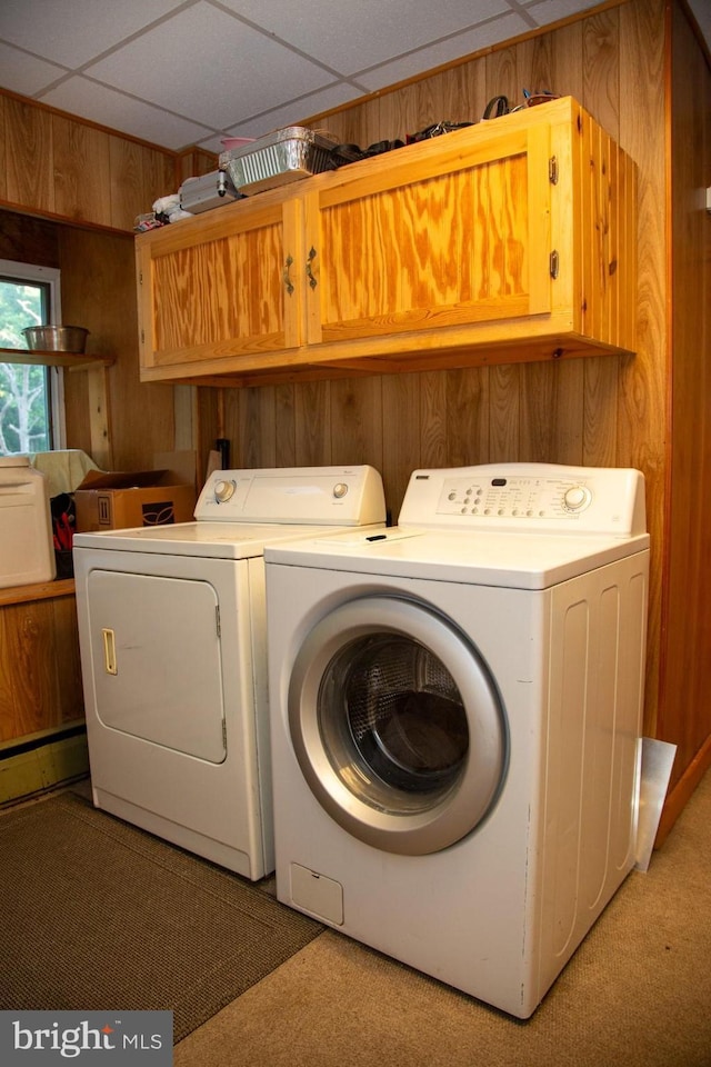 washroom featuring wood walls, cabinets, light carpet, and washing machine and clothes dryer