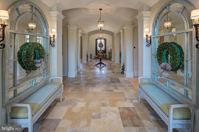 foyer with a chandelier, decorative columns, and vaulted ceiling