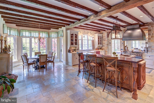 kitchen featuring plenty of natural light, beamed ceiling, and an inviting chandelier