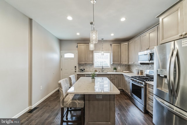 kitchen featuring a center island, backsplash, sink, appliances with stainless steel finishes, and decorative light fixtures