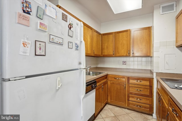 kitchen featuring decorative backsplash, sink, light tile patterned floors, and white appliances