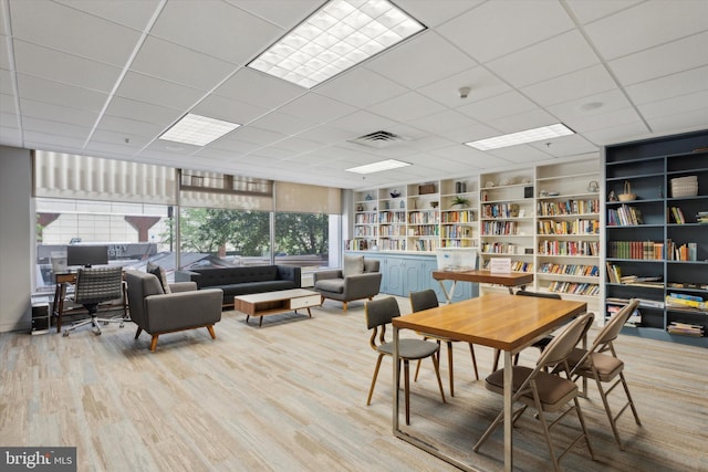 dining area with a drop ceiling and light wood-type flooring