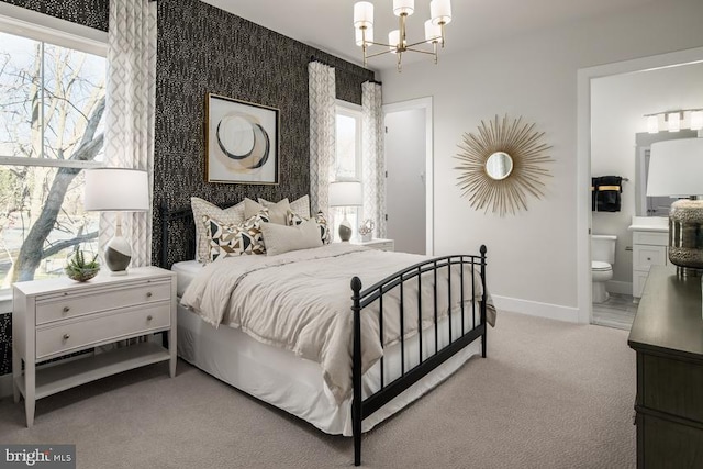 carpeted bedroom with ensuite bathroom and a chandelier