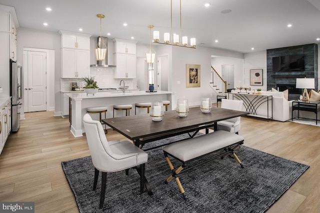 dining space with sink, a tiled fireplace, and light wood-type flooring