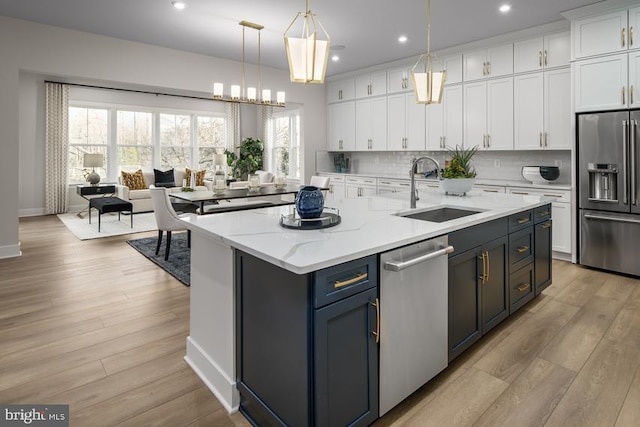 kitchen with white cabinetry, a center island with sink, stainless steel appliances, pendant lighting, and sink