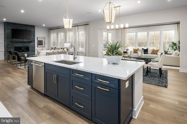 kitchen featuring sink, hanging light fixtures, dishwasher, and an island with sink