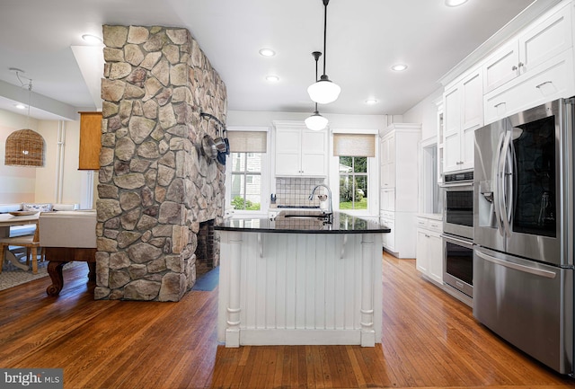 kitchen with appliances with stainless steel finishes, dark hardwood / wood-style floors, white cabinetry, and hanging light fixtures