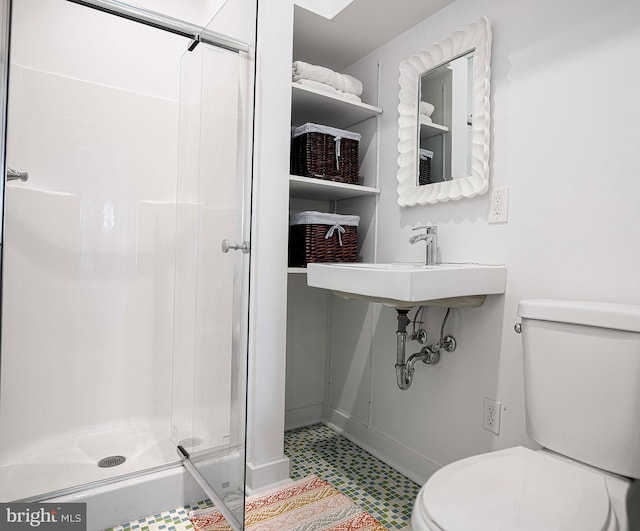 bathroom featuring toilet, a shower with door, and sink