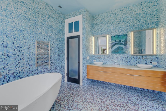 bathroom featuring a tub, vanity, and tile walls