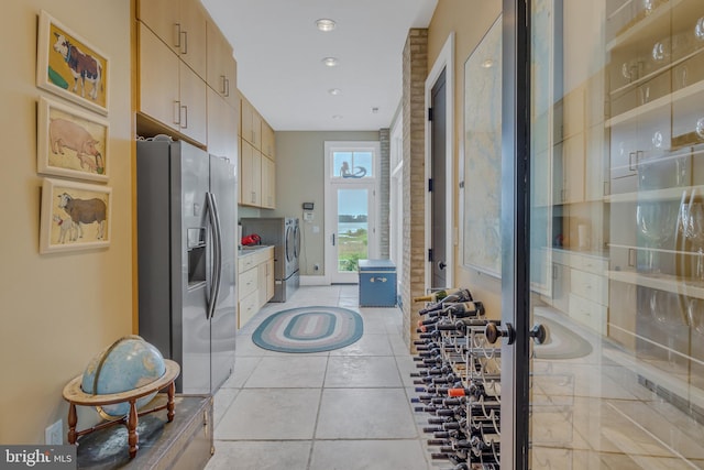 kitchen featuring stainless steel fridge, independent washer and dryer, light tile patterned floors, and light brown cabinetry