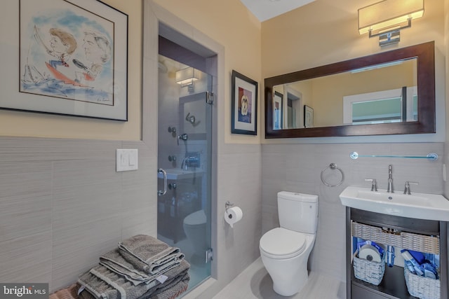 bathroom featuring vanity, a shower with door, toilet, and tile walls