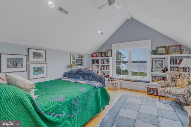 bedroom featuring lofted ceiling with beams, hardwood / wood-style flooring, ceiling fan, and a water view