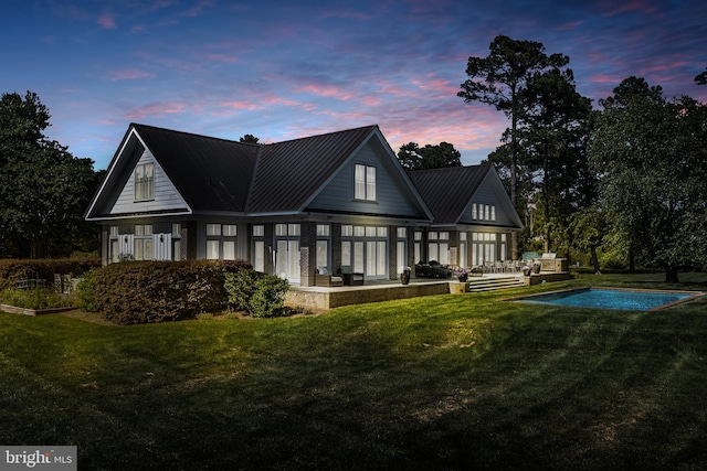 back house at dusk featuring a yard