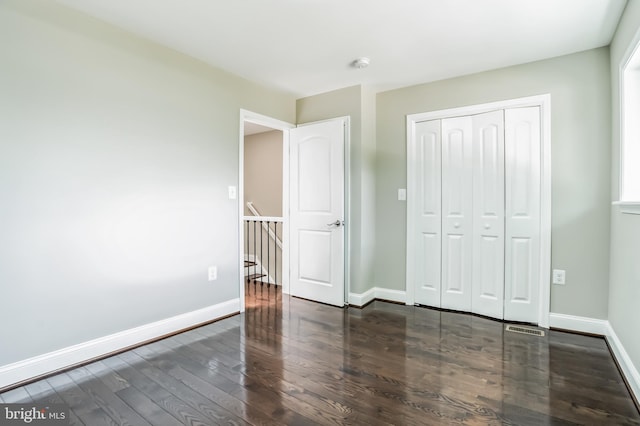 unfurnished bedroom featuring dark hardwood / wood-style flooring and a closet