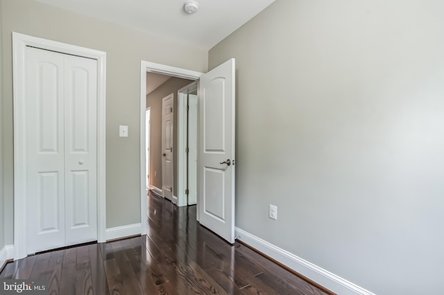 unfurnished bedroom featuring dark wood-type flooring and a closet