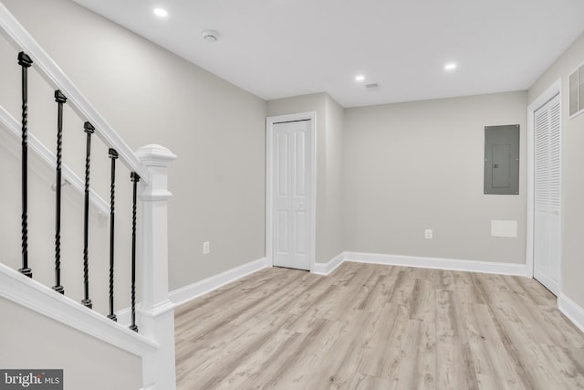 interior space featuring electric panel and light hardwood / wood-style flooring