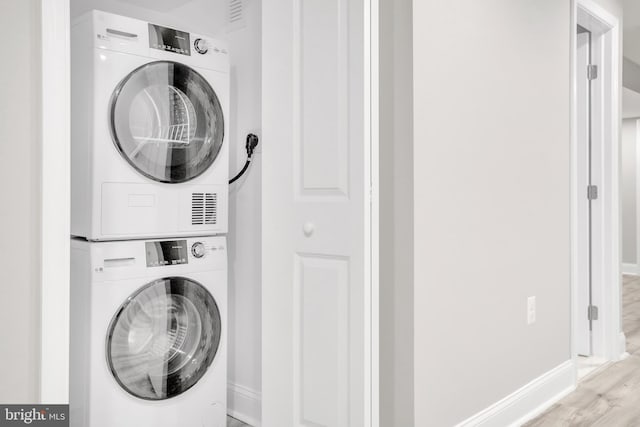 laundry area with light wood-type flooring and stacked washer / drying machine