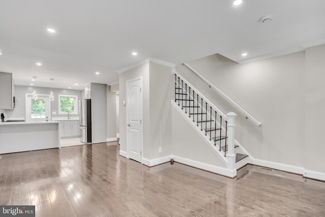 unfurnished living room with hardwood / wood-style floors and ornamental molding