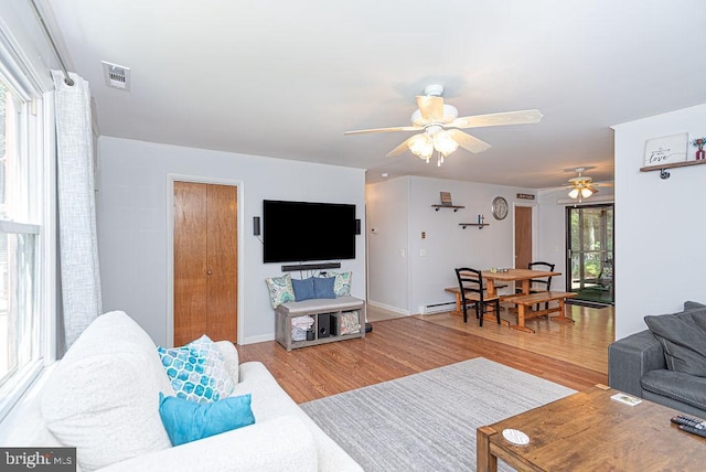 living room featuring wood-type flooring, a baseboard radiator, plenty of natural light, and ceiling fan