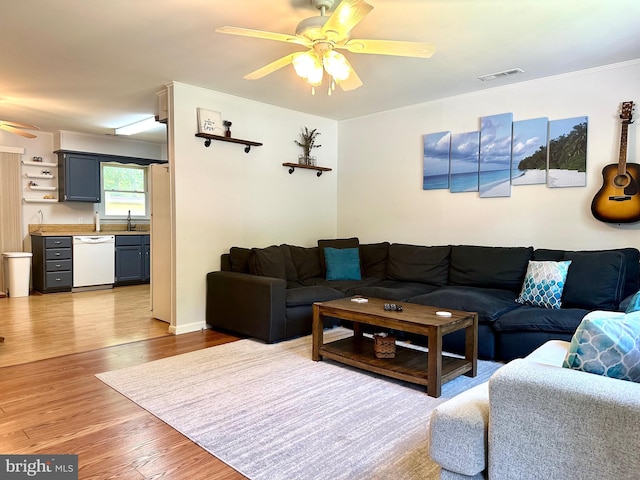 living room with light hardwood / wood-style floors, ceiling fan, and sink