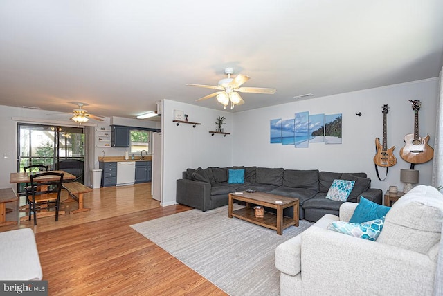 living room featuring ceiling fan, hardwood / wood-style floors, and sink