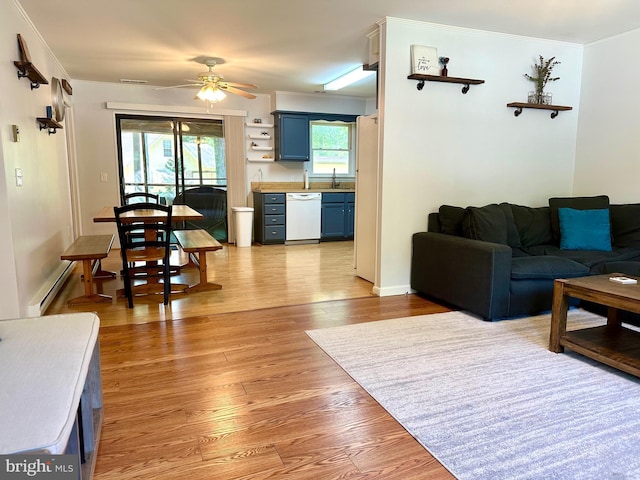 living room featuring baseboard heating, ceiling fan, light hardwood / wood-style flooring, and a healthy amount of sunlight