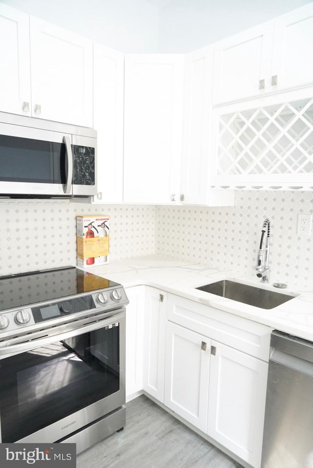 kitchen featuring white cabinets, stainless steel appliances, light stone counters, and sink