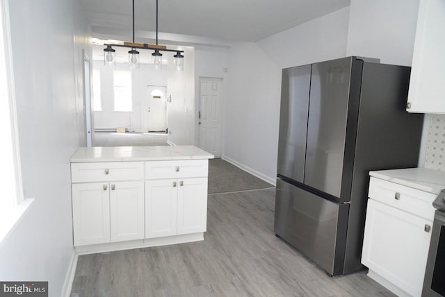 kitchen with stainless steel fridge, light hardwood / wood-style flooring, and white cabinets