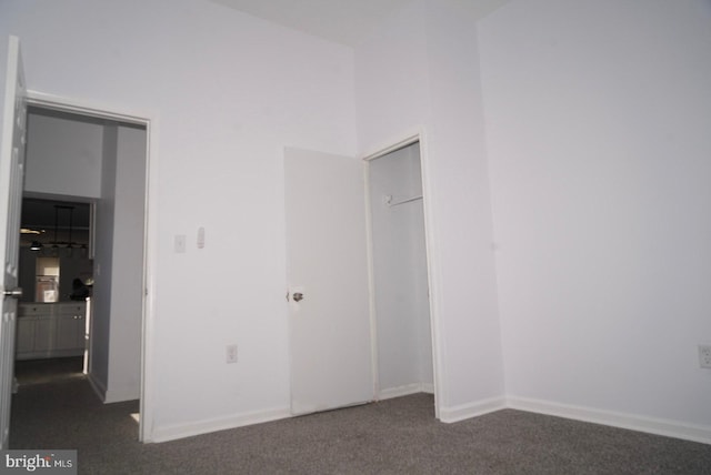 unfurnished bedroom with a closet and dark carpet