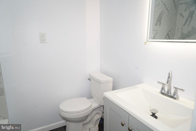 bathroom with toilet, vanity, and baseboards