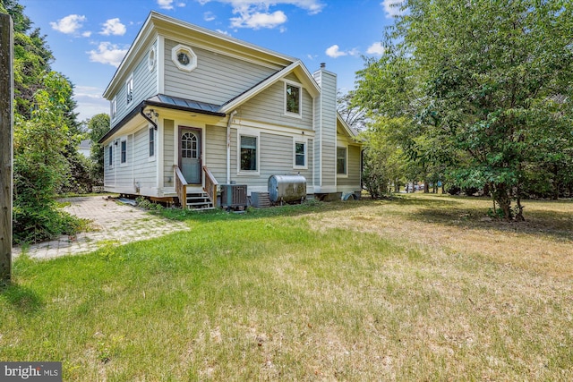 back of property featuring a lawn and cooling unit