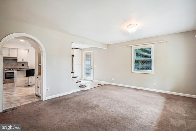 carpeted spare room featuring a notable chandelier